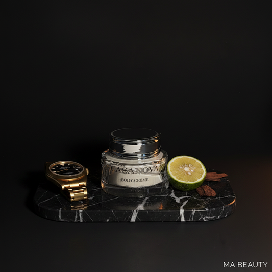 Jar of Casanova body crème on a dark marble tray with a gold watch and lemon slice, against a black background.