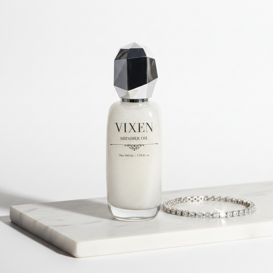 Vixen shimmer oil bottle with geometric cap on a white surface, next to a bracelet.